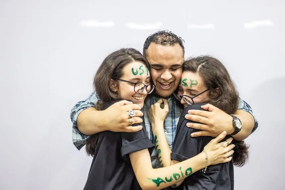 Alunas aprovadas na USP se abraçando com um professor da Ohmori