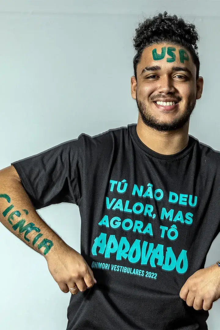 Aluno aprovado na USP sorrindo, com a faculdade escrita na testa e no braço