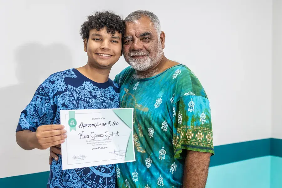 Kauã com o certificado de aprovação na ETEC, ao lado de um familiar
